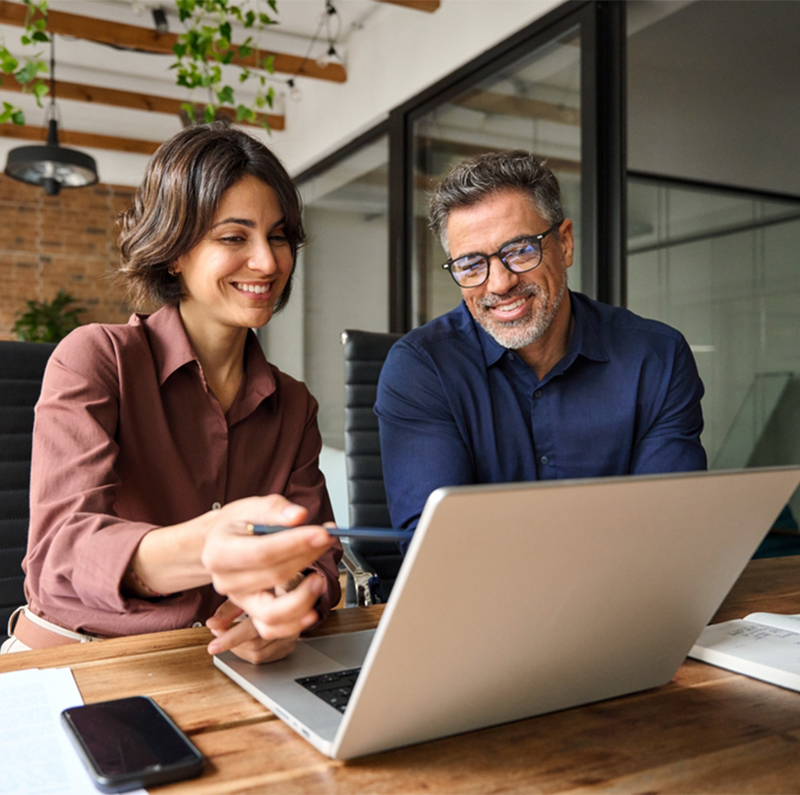 Business,Team,Of,Two,Executives,Working,Together,Using,Laptop,In
